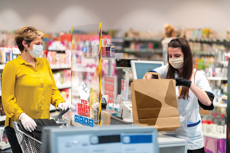 Customer at a store with a social distancing barrier with ClingZ® signage