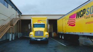 WCP Solutions' big yellow truck parked in front of loading dock at a warehouse
