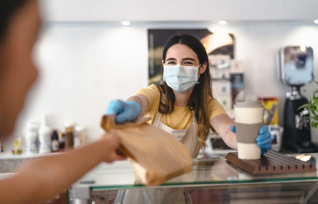 Coffee shop handing to-go cup and bag to customer