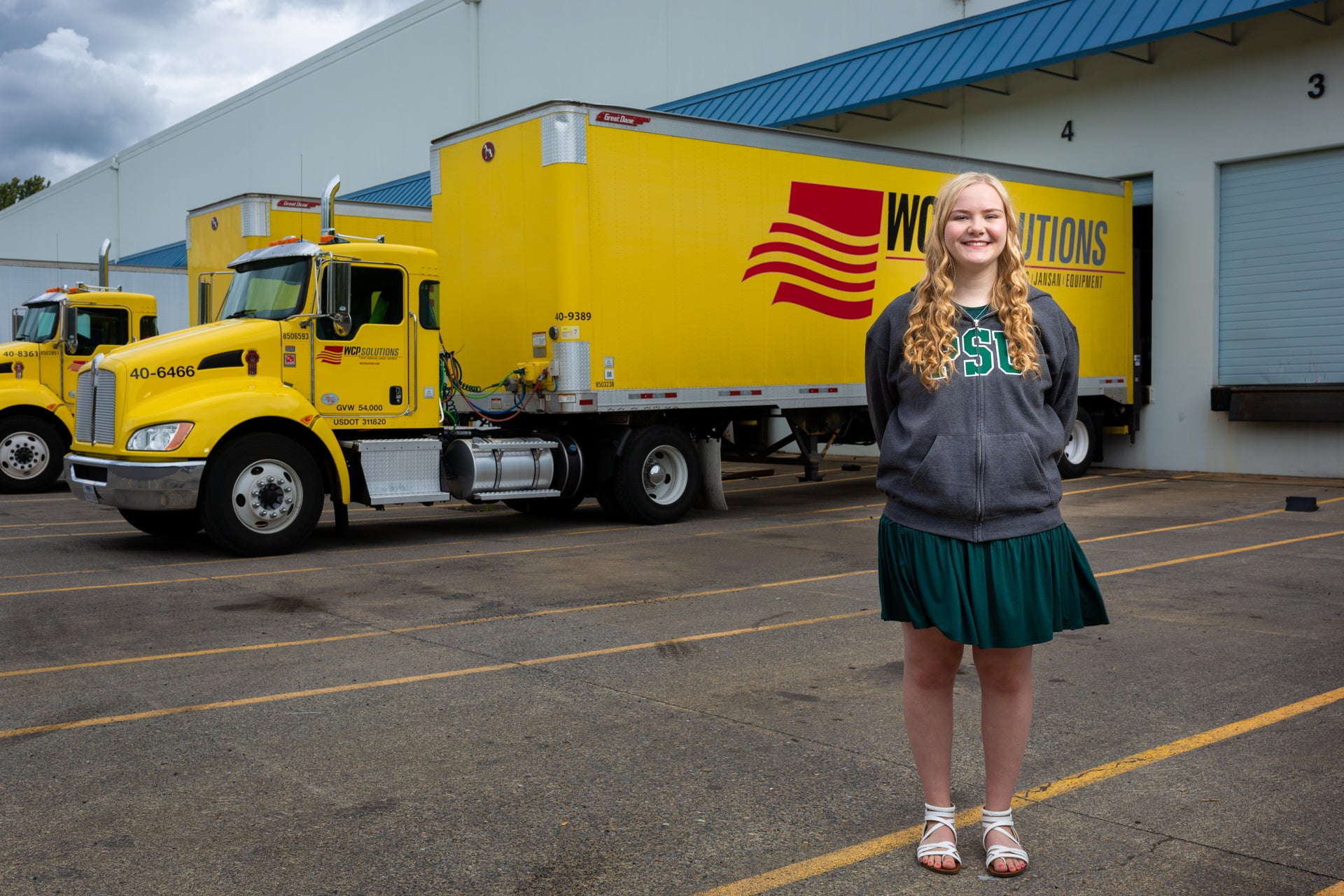 Evie Thompson standing in front of WCP Solutions yellow delivery truck