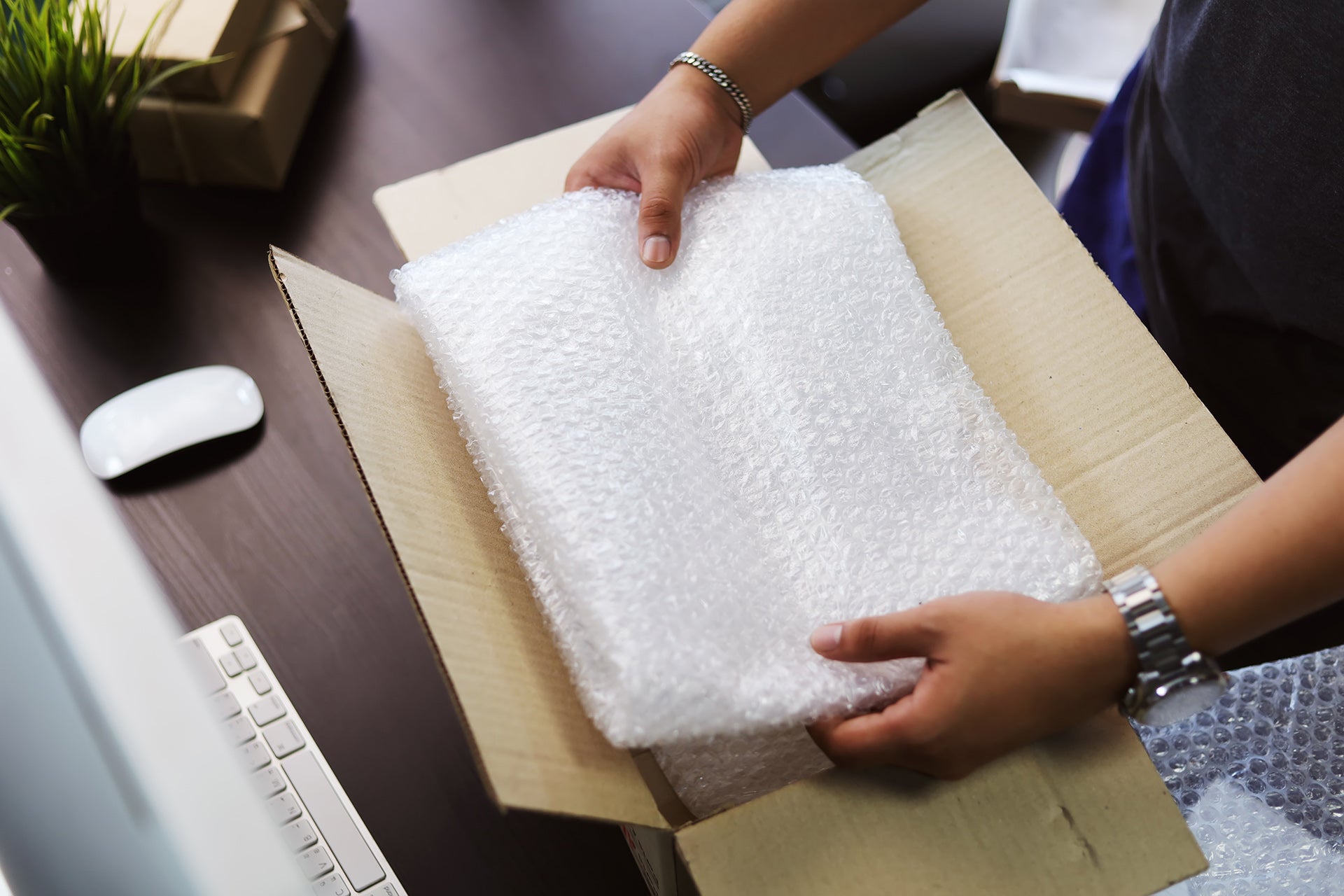 person inserting bubble wrap into a corrugated box for protective packaging