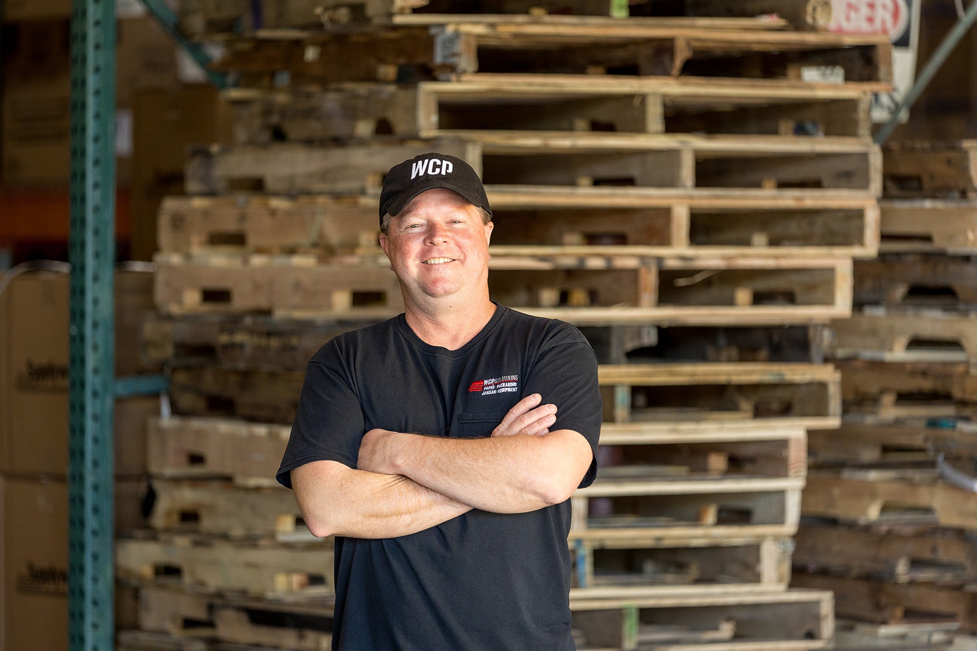 Chris standing in front of a pile of pallets