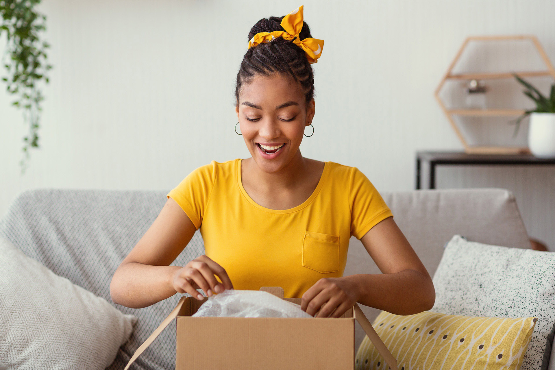 Woman opening up a corrugated shipping box on a couch